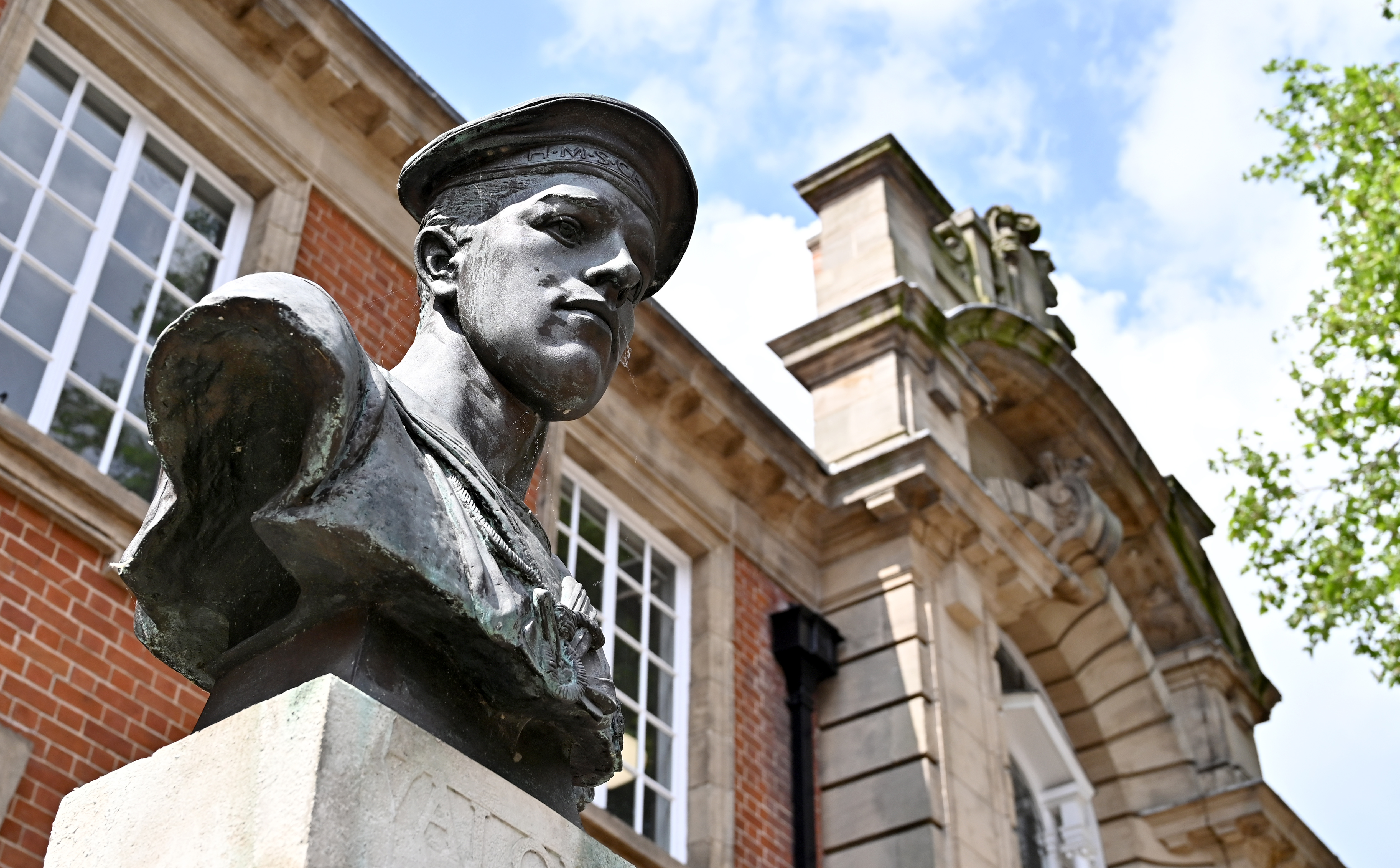 A bronze bust of John Henry Carless, a WW1 hero, with a historic building in the background